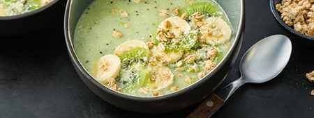 Groene smoothiebowl met kiwi, banaan, kokos en muesli